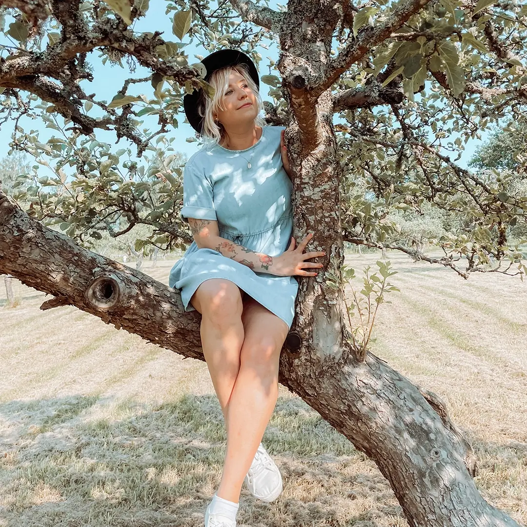 Tjej som sitter uppe i ett träd på sommaren